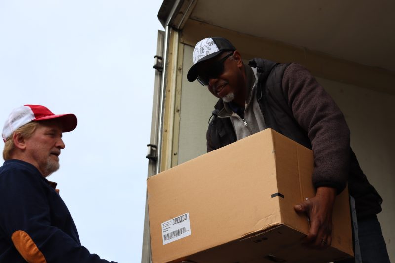 Ronald Buckman assists tribal staff member Tiger Paulk to unload some goods.