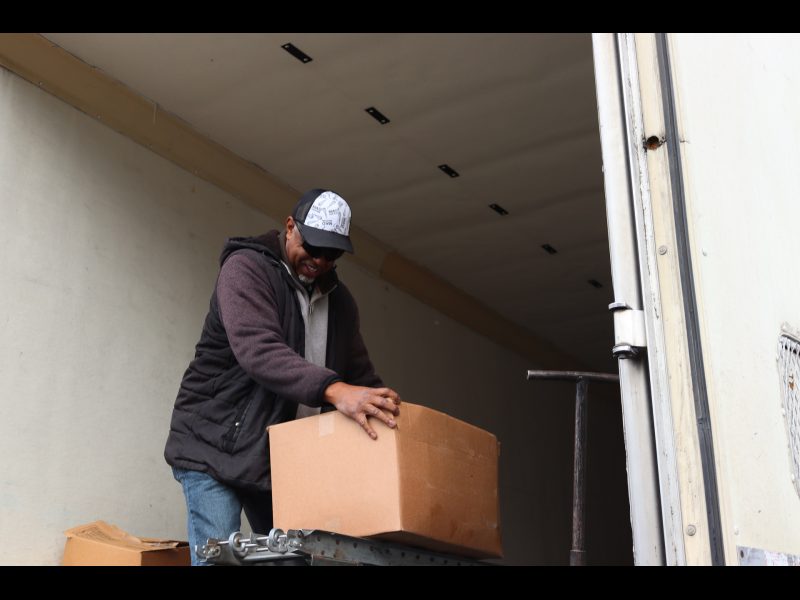 The last of one distribution being rolled out on conveyor. Ronald Buckman rolling some goods box on a conveyor.