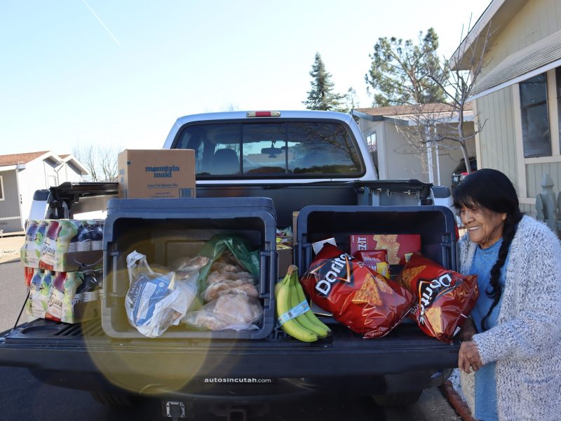 Program Director Mildred Burley happily looks on the bounty of this delivery that will be shared by tribal members, which includes Chips, teas, frozen meats, fruits, crackers and miscellaneous. Miwok tribal elder Mildred Burley loading goods onto truck during the February 2024 Food For Tribal Families Program.