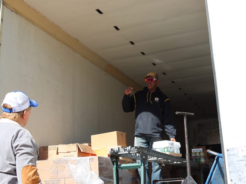 The beginning of a larger distribution can be seen on conveyor as specialist Ronald Buckman speaks to staff. Ronald Buckman speaking to tribal staff Tiger Paulk during the food distribution in April 2024.