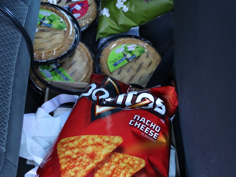 This picture shows many snack and dessert items along with multiple fruits which include a full flat of strawberries.