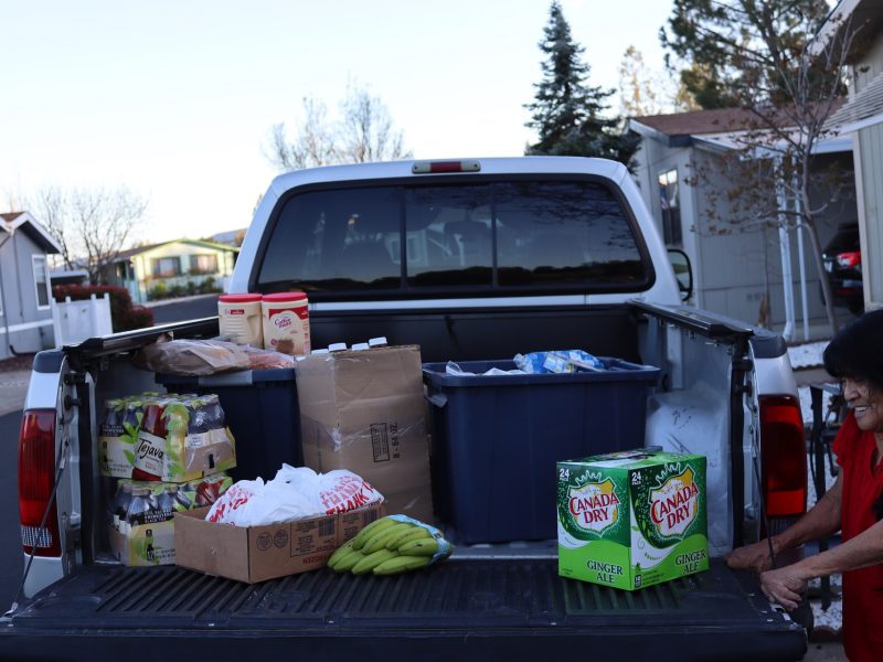 Food for Tribal Families Director Mildred Burley stands next to an allotment of various beverages, dry and frozen foods during the April 2024 distribution.