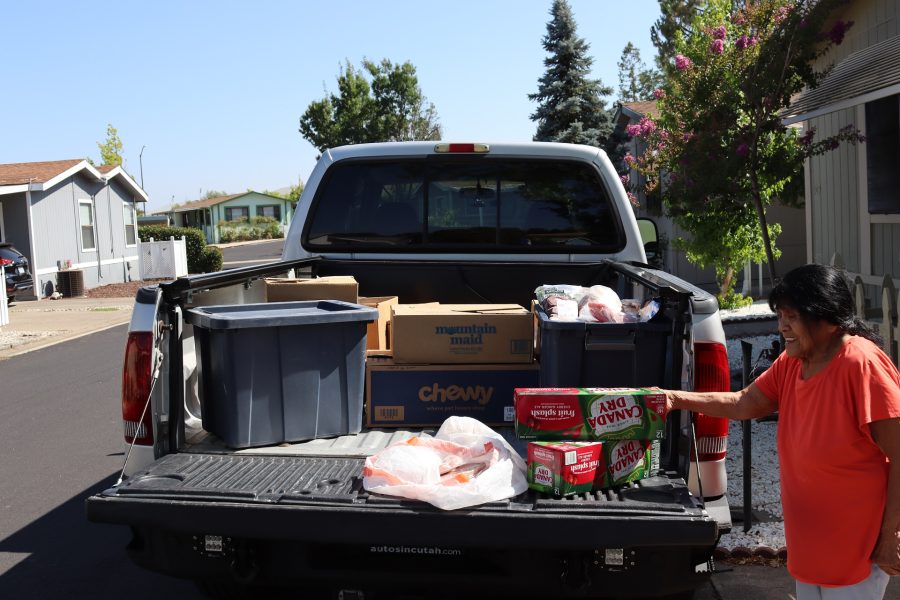 Program Director Mildred Burley always happy when she is given the necessities to be able to make a difference in the lives of tribal families. Tribal Elder Mildred Burley smiling while loading groceries into a truck, getting ready to help tribal families in need.