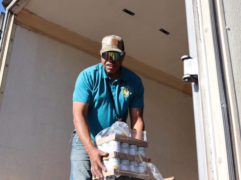 Ronald Buckman helps Tiger Paulk unloading goods during a food distribution in October 2024.