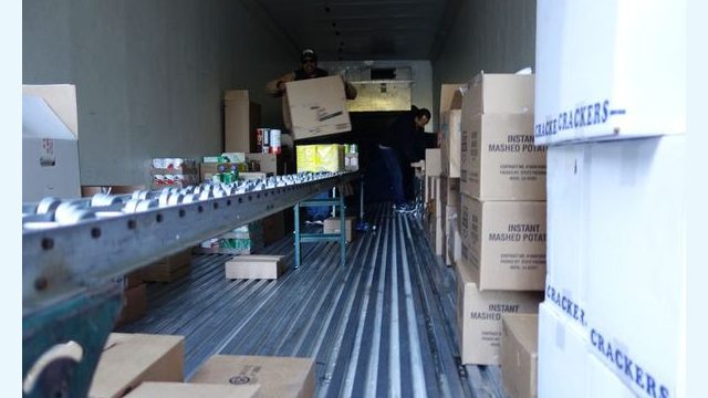 Inside the distribution truck, Tule River USDA Food Distribution staff members Ronald Buckman and Jesus Salas sort and package commodity foods to be given to needy food distribution program participants.