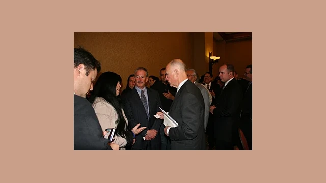 Chairperson Silvia Burley of the California Valley Miwok Tribe speaks in-depth personally to an attentive Jerry Brown, Governor of California, of the many issues that the Governor had earlier expressed concern over, (as others standing close by listen in). Note: The Governor is seen here holding the Chairperson's tribal business card.